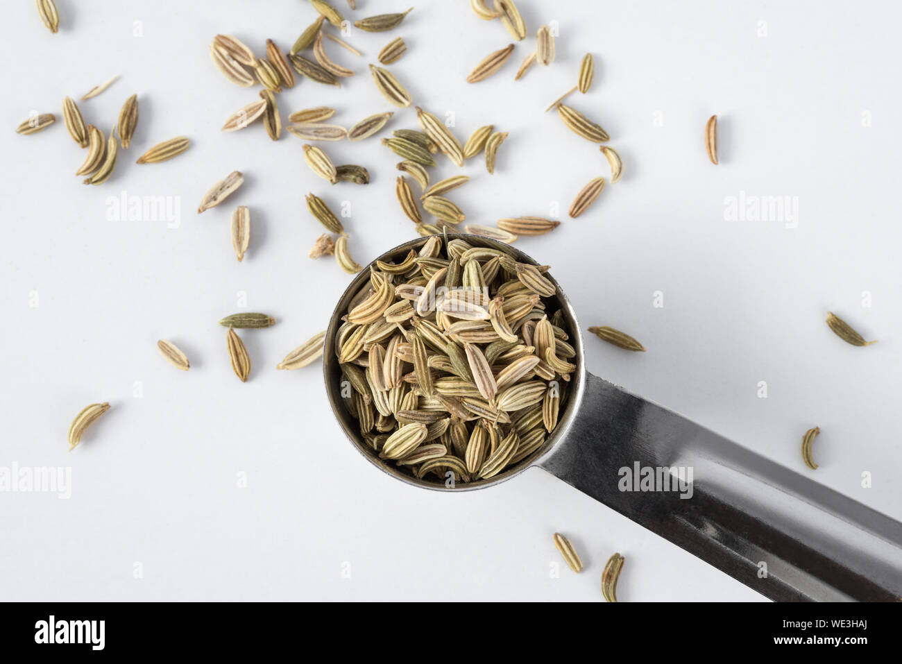 High Angle View Of Fennel Seeds In Measuring Spoon Against White Background Stock Photo