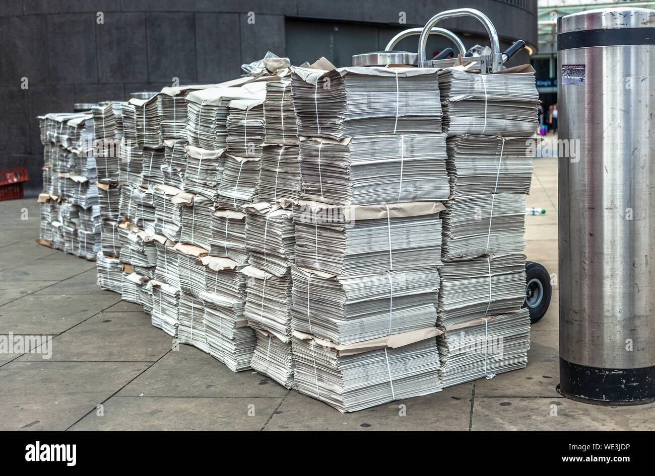 Rows of newspaper stacks lined up on a pavement, London, England, UK