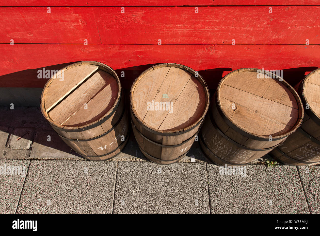 High Angle View Of Wooden Barrels On Footpath By Red Wall Stock Photo