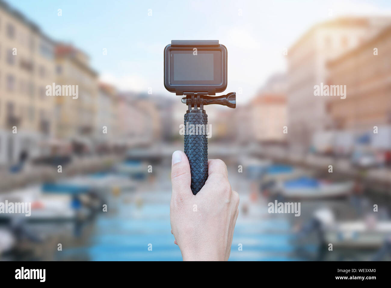 Action camera on stick in hand recording city concept. Blank screen for mockup. Stock Photo