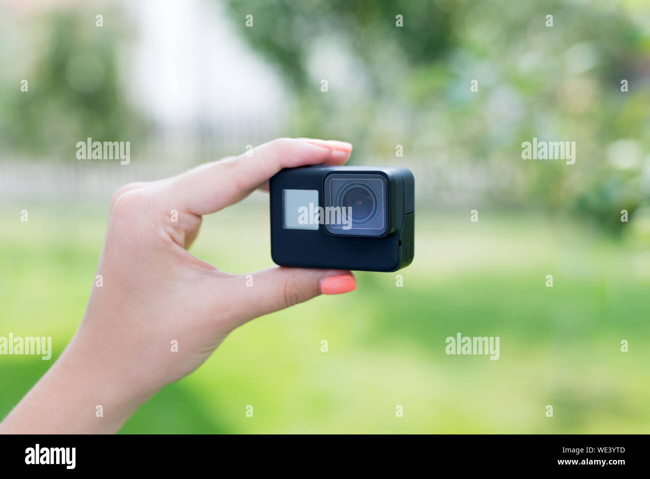 Making a selfie with action camera concept. Camera in woman hand. Close-up. Stock Photo
