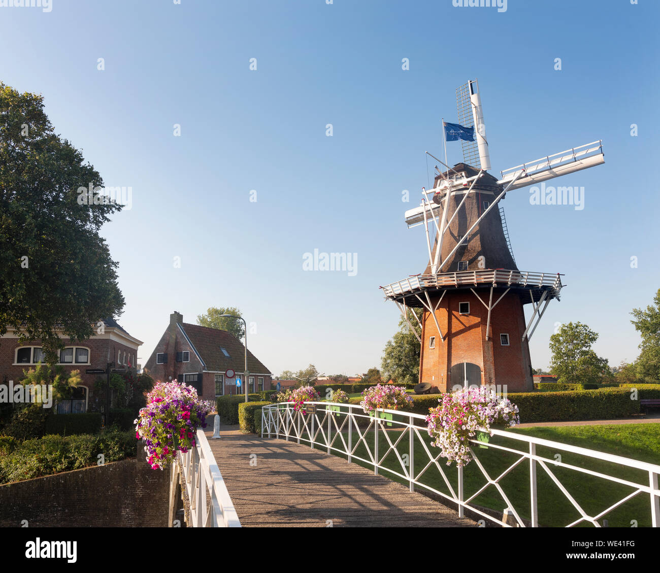 flowers on bridge and old windmill in dutch town of dokkum Stock Photo