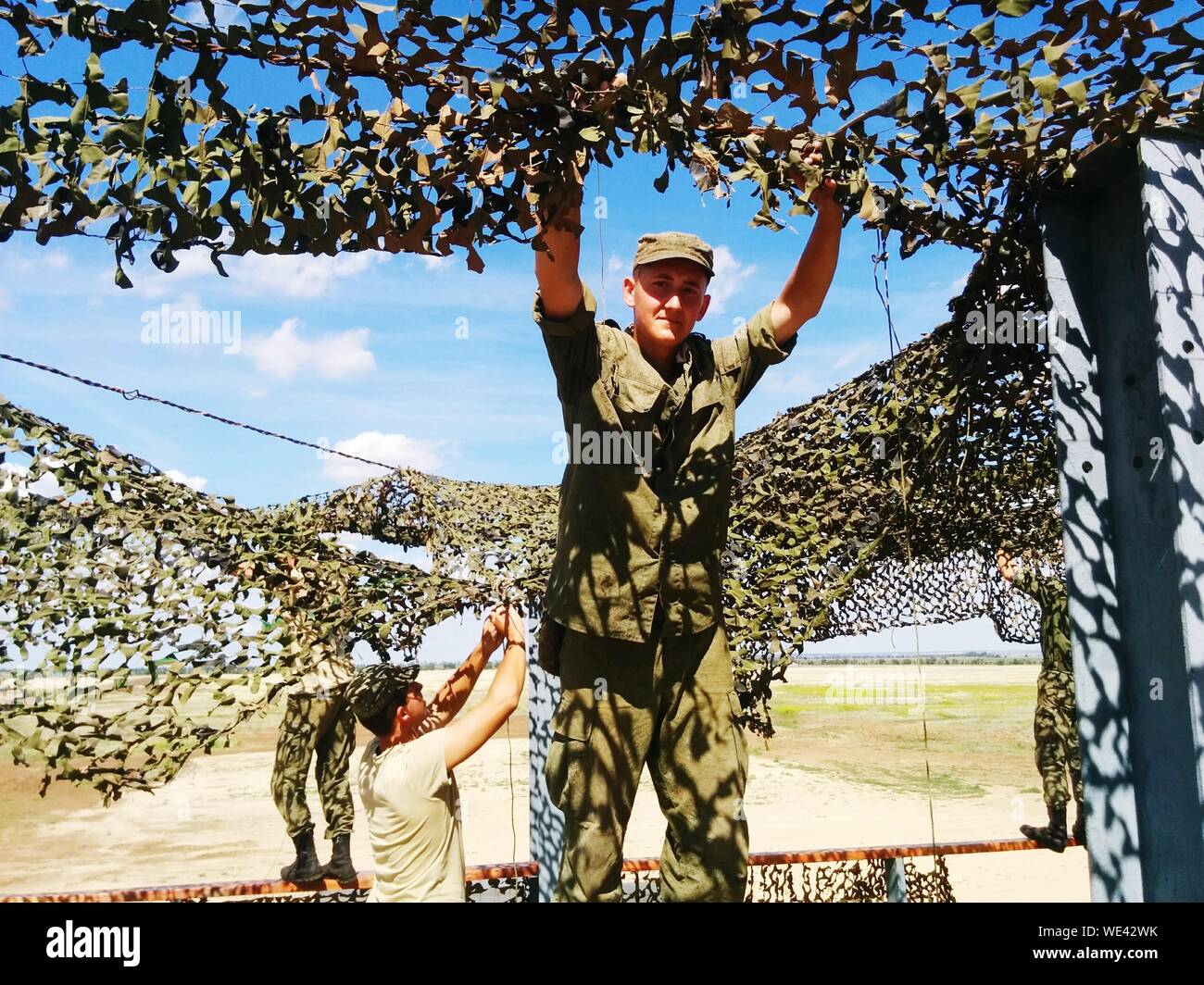 Portrait Of Male Army Soldier Standing Amidst Nets On Field Stock Photo