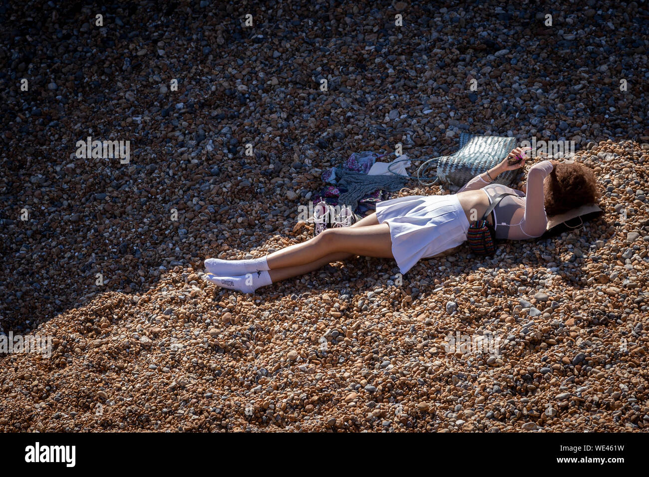 young woman lying on brighton beach texting Stock Photo