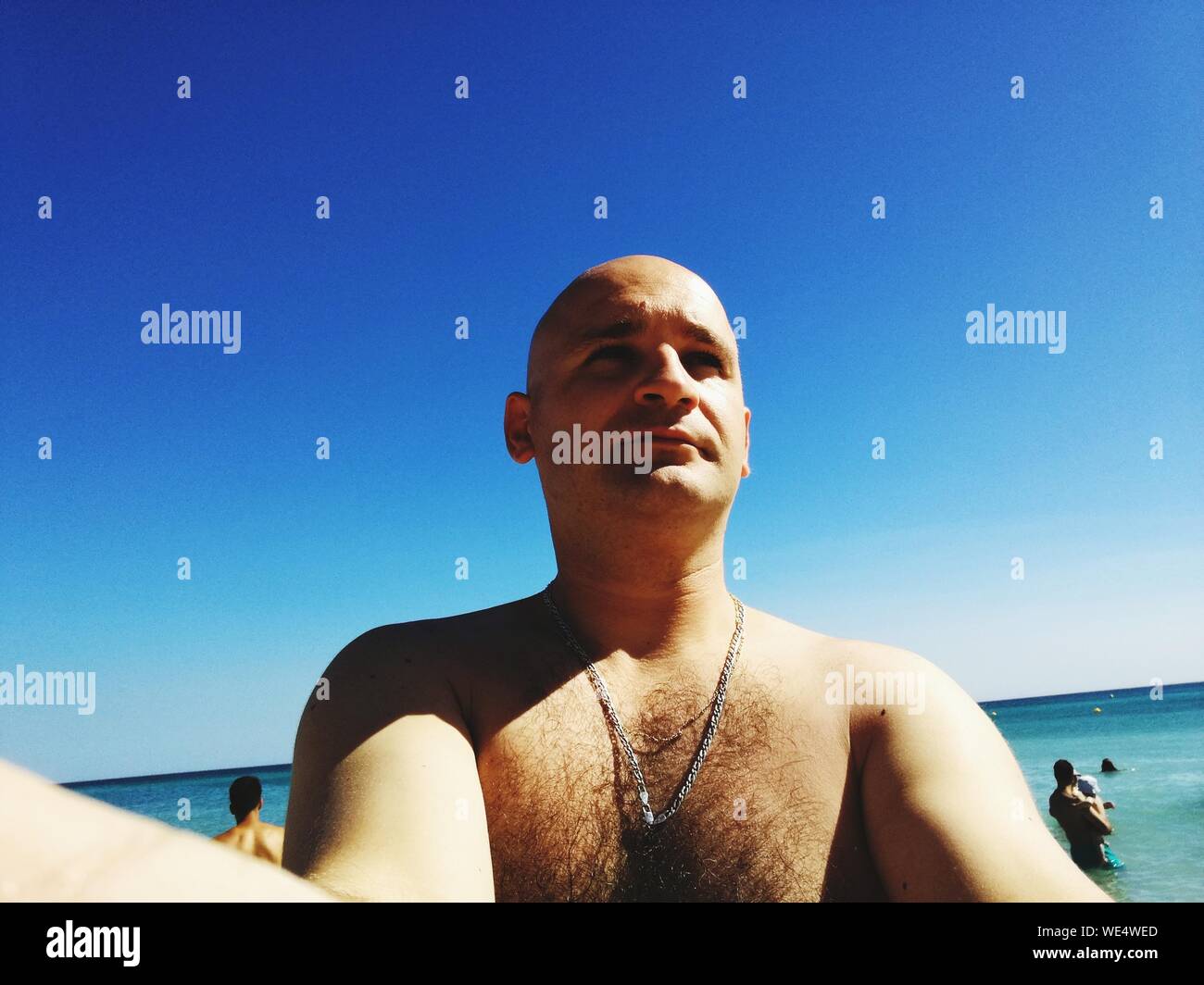 Mid Adult Man By Sea Against Clear Blue Sky Stock Photo