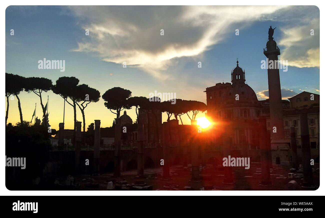 Silhouette Trees By Via Dei Fori Imperiali Against Cloudy Sky During Sunset Stock Photo