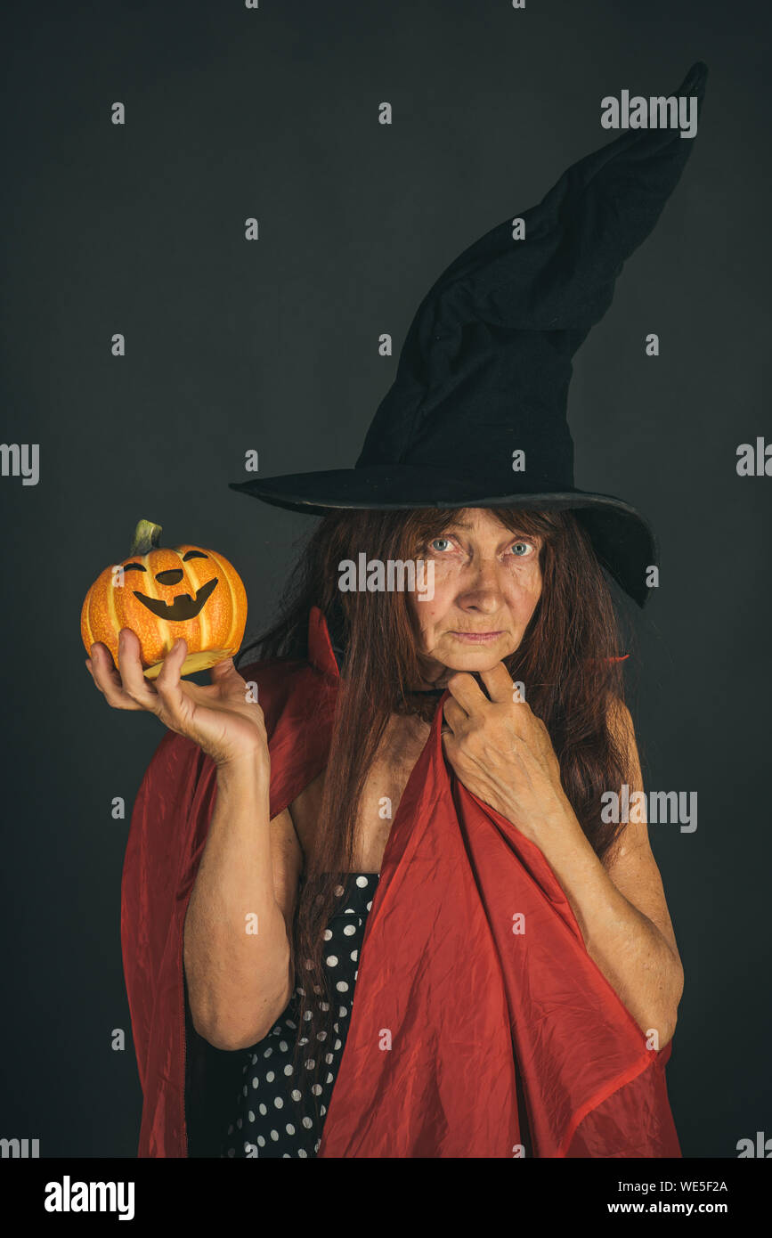 Halloween senior lady holding pumpkin on black background Stock Photo ...