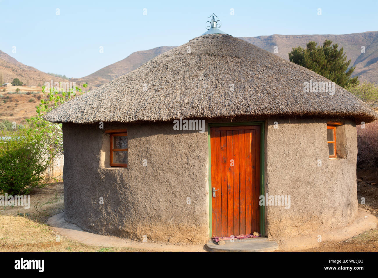 Traditional african round clay house with thatched roof in village, Lesotho, Southern Africa, basotho people national old home, Drakensberg mountains Stock Photo