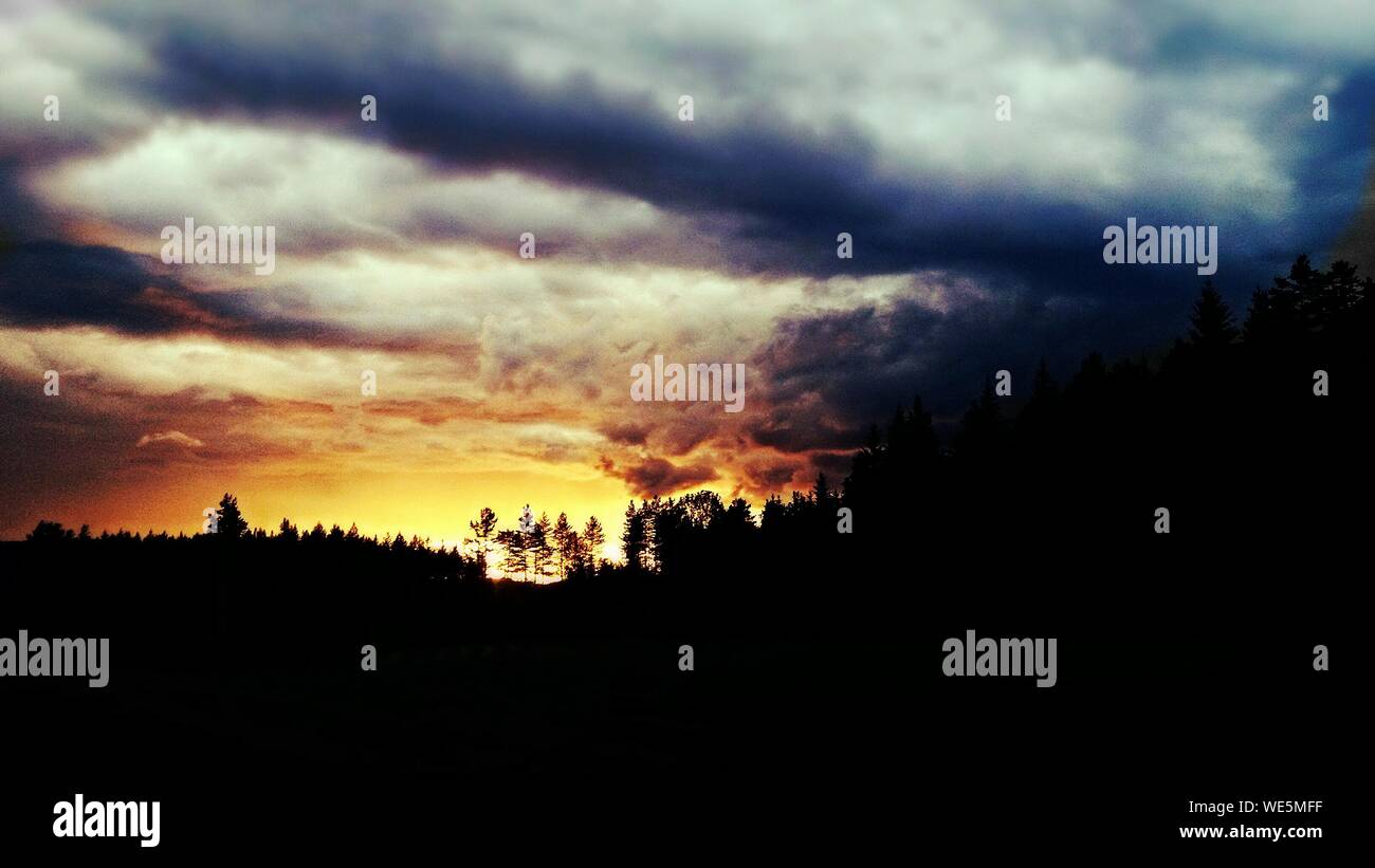 Low Angle View Silhouette Land Against Cloudy Sky During Sunset Stock Photo