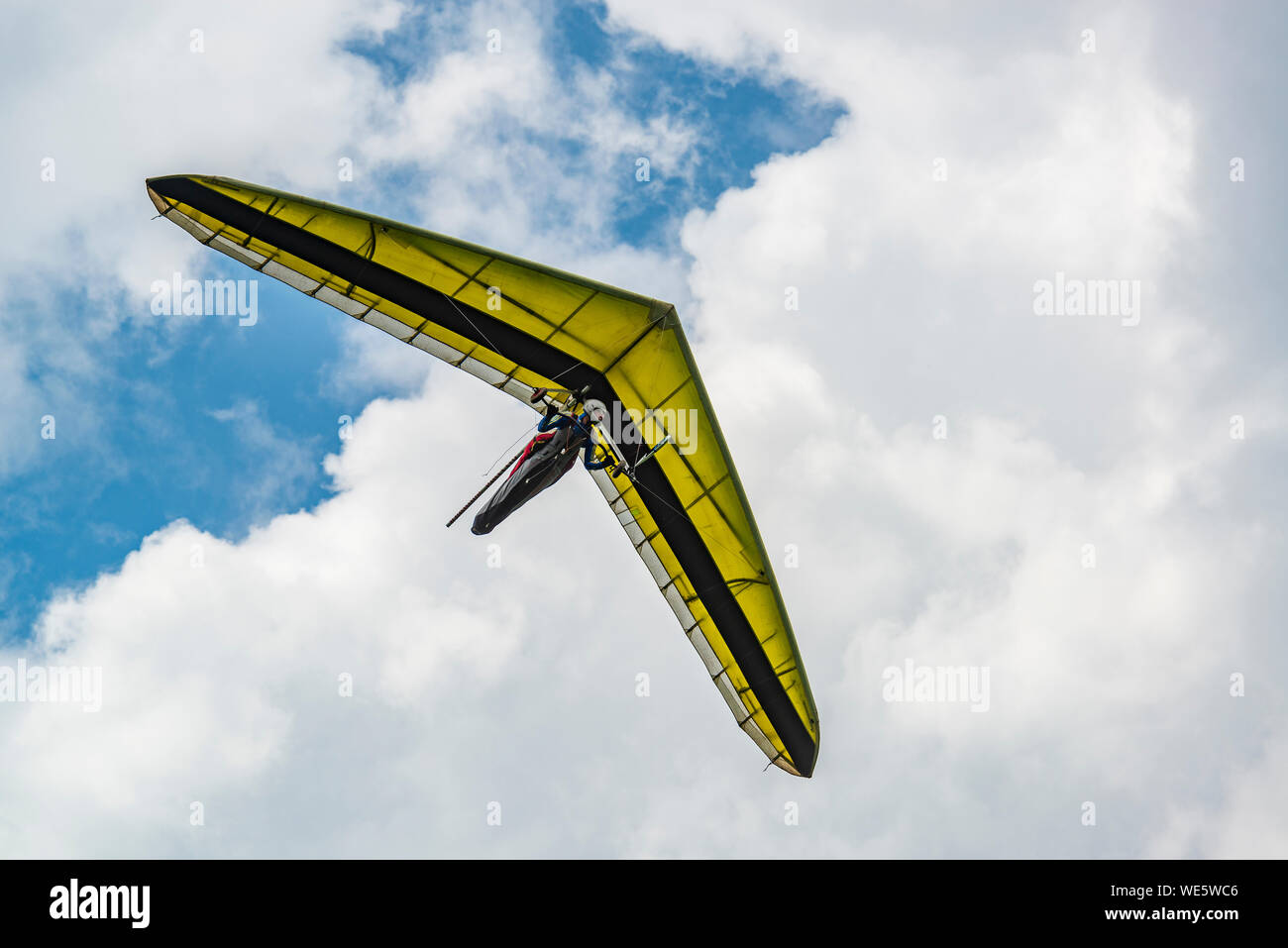 Yellow hang glider wing with cloudy sky on the background. Hangglider pilot and his aircraft. Stock Photo