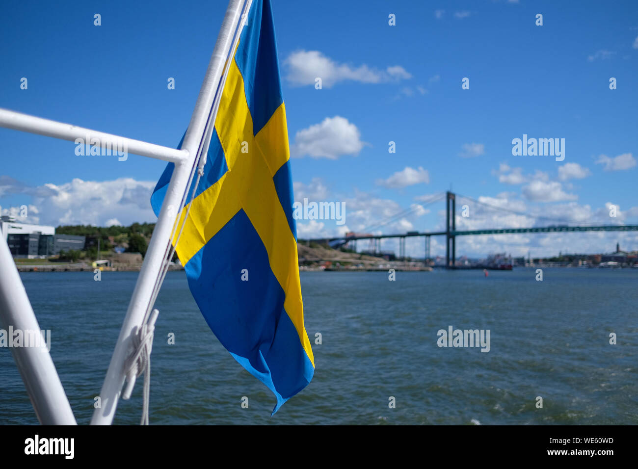 Swedish Flag In Boat Moving On River Against Bridge Stock Photo
