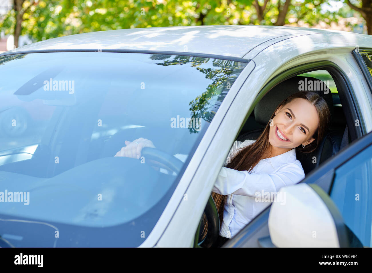 Beautiful smiling brunette girl behind the wheel of a car Stock Photo