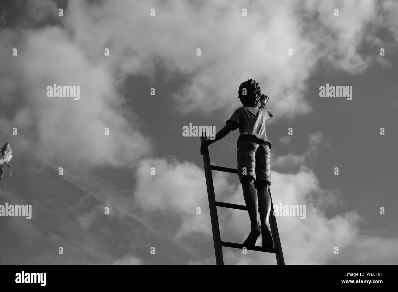 Black and white picture of Lake side statue of boy climbing ladder Stock Photo