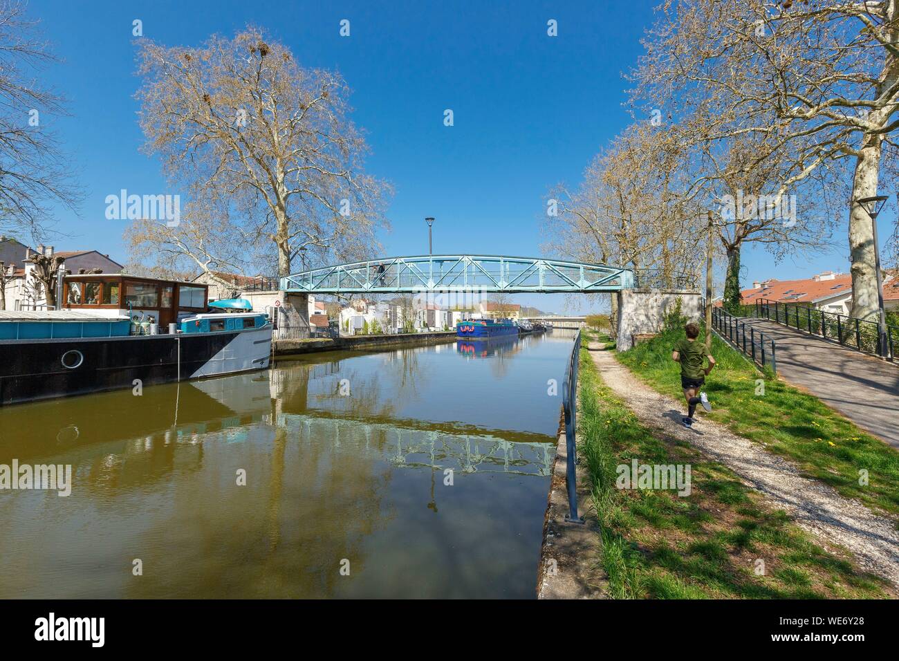 France, Meurthe et Moselle, Nancy, apartment buildings, houses, flat boats and jogger along the Meurthe canal Stock Photo
