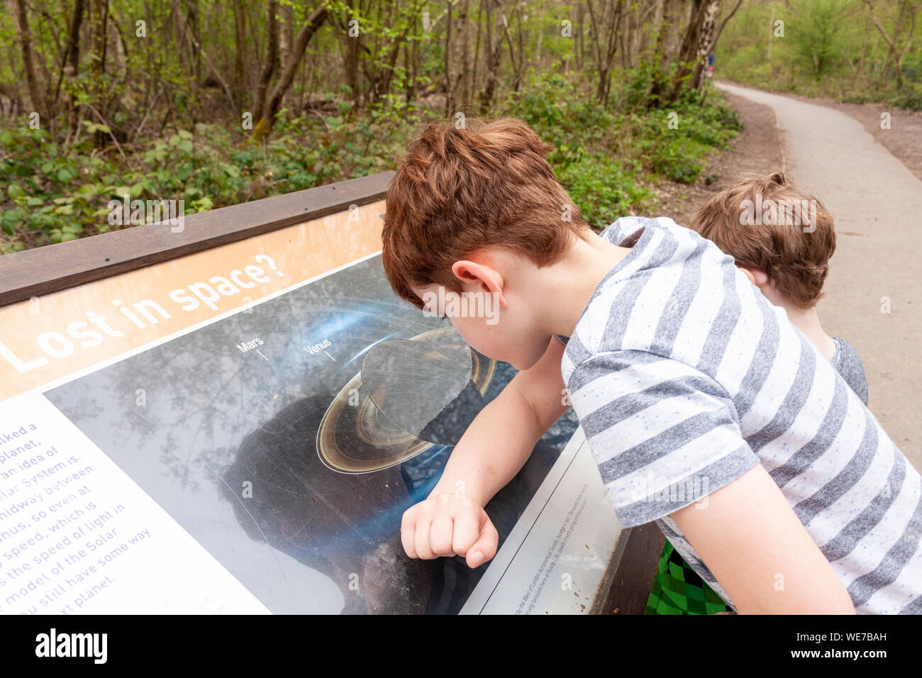 A boy looking at and reading a board about the solar system at Ruislip Lido, Greater London Stock Photo