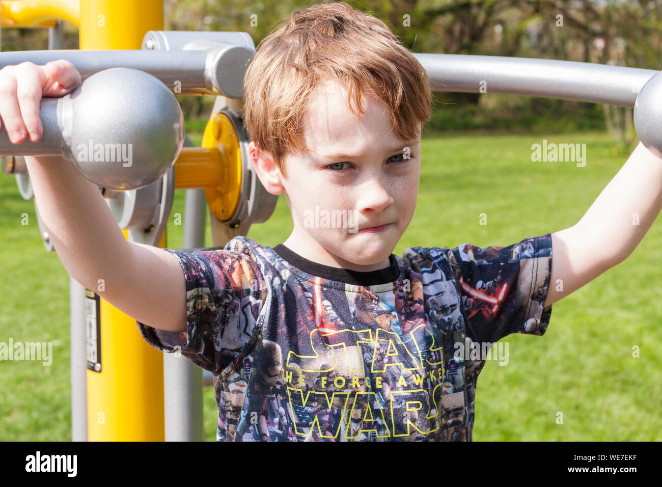 A young boy using the outdoor exercise machine in a park gym Stock