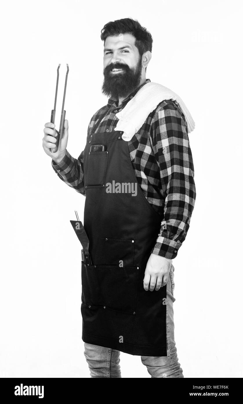 Keeping his hand far from flame. Bearded man holding barbecue tongs in hands. Grill cook using kitchen tongs. Chef hipster holding stainless steel tongs. Cooking tongs for preparing and serving food. Stock Photo