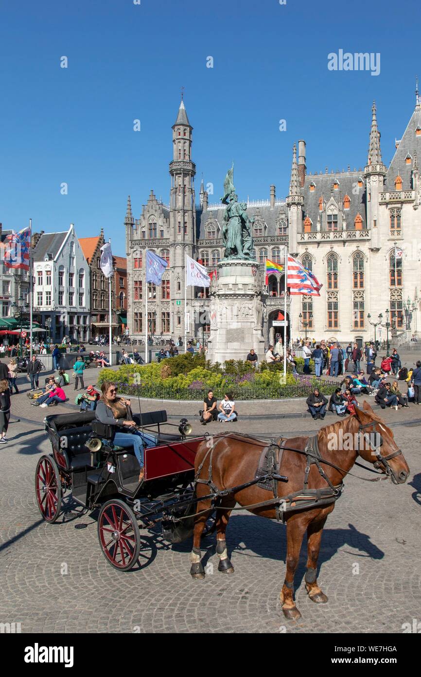 Belgium, Western Flanders, Bruges, historical centre listed as World Heritage by UNESCO, carriage in front of the statue of Jan Breydel and Pieter de Coninck who led the Bruges Mornings of 1302 massacring the supporters of the King of France with the Provincial Palace of neo-Gothic style in the background Stock Photo