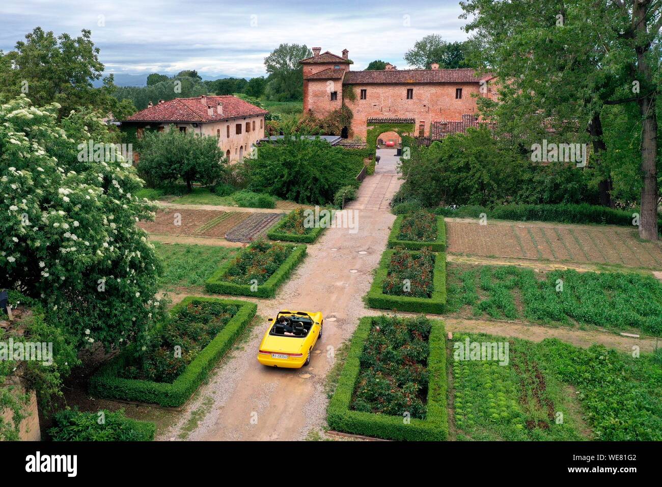 Italy, Emilia Romagna, Polesine Zibello near Parma, Antica Corte Pallavicina Hotel and restaurant, Alfa Romeo Duetto Spider yellow cabriolet (aerial view) Stock Photo