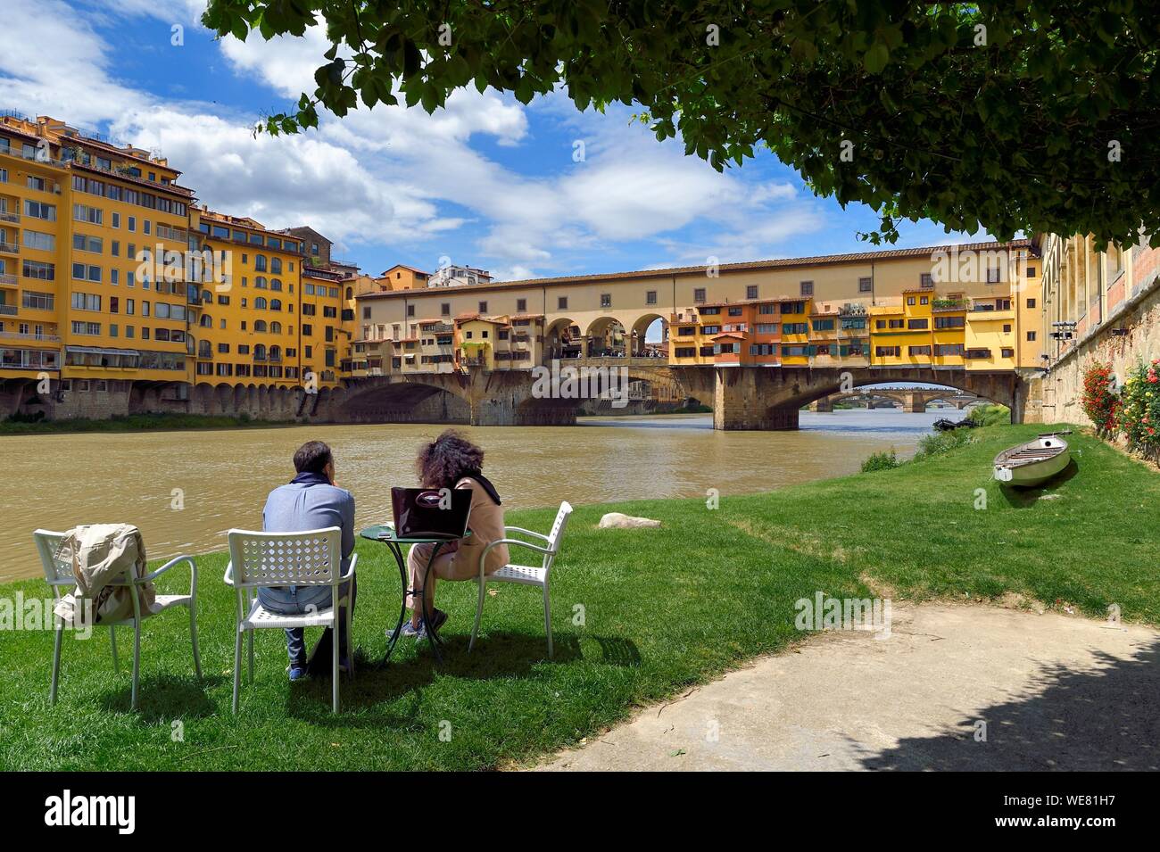 Italy, Tuscany, Florence, listed as World Heritage by UNESCO, the Ponte Vecchio seen from the Societa Canottieri Firenze (Florence Rowing Club), club members having a rest on the edge of the Arno River Stock Photo