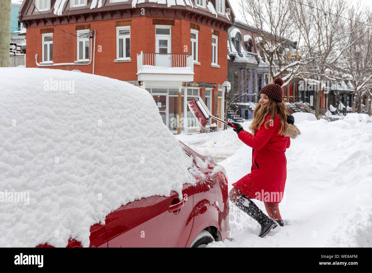 Canada, Quebec province, Montreal, Plateau-Mont-Royal neighborhood after a snowstorm, a woman snowdrifts her car with a snow broom Stock Photo