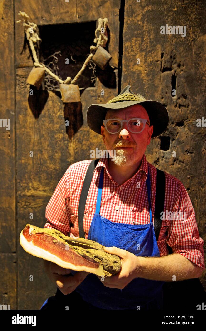 Italy, autonomous province of Bolzano, Brunico, seller of the speck museum shop wearing a hat with a piece of speck in his hands Stock Photo