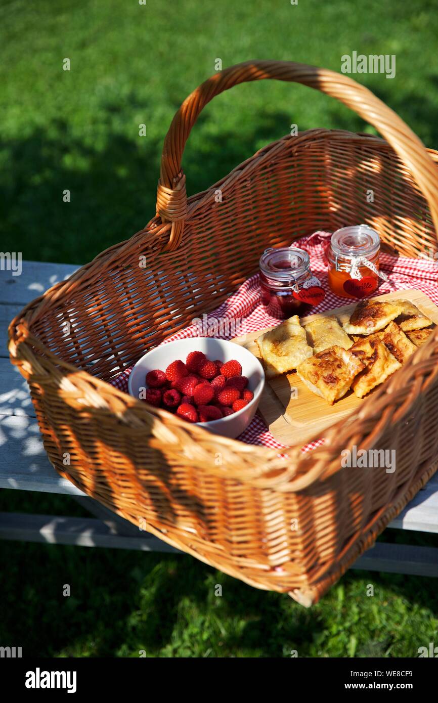 Italy, autonomous province of Bolzano, picnic basket filled with raspberries and jams in the garden of the Grushof alpine farm located in the heights of Glorenza Stock Photo