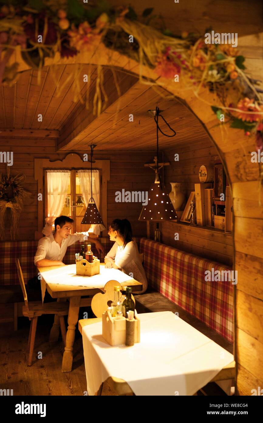 Italy, autonomous province of Bolzano, San Candido, young couple installed in an alcove of the pizzeria helmhotel installed in the wooded decoration of an old sheepfold Stock Photo