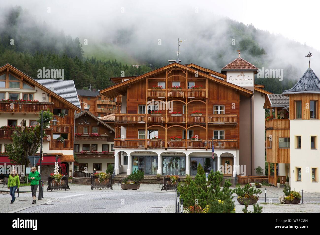 Italy, autonomous province of Bolzano, San Vigilio, wooden chalets in the city center with the side of a green mountain in the background Stock Photo