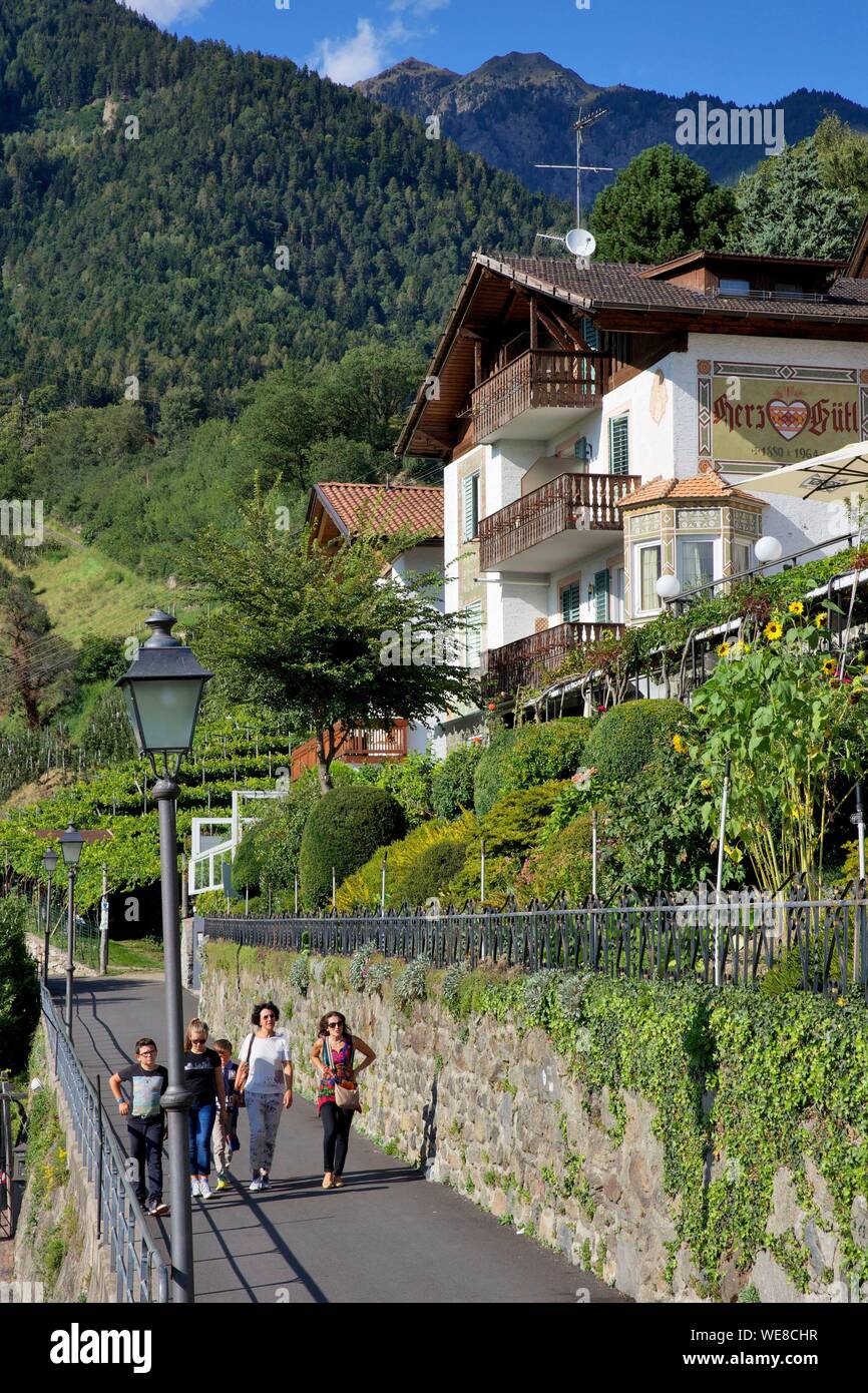 Italy, autonomous province of Bolzano, Tirol, family walking at the foot of a chalet in Tirol, the village that gave its name to the Tyrol region Stock Photo