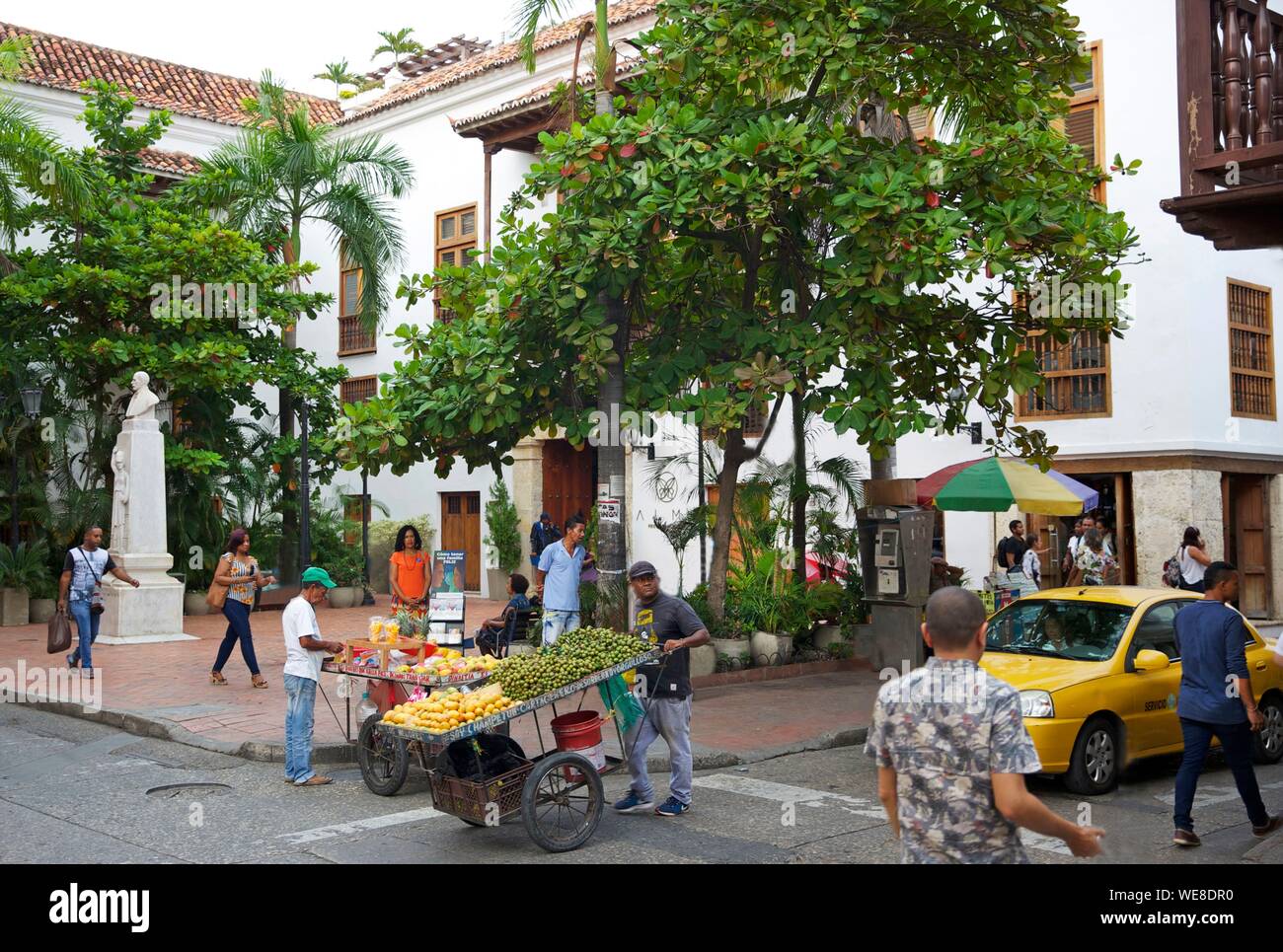 Colombia, Bolivar Department, Cartagena, listed as World Heritage by UNESCO, street vendor pulling a fruit cart in the middle of passing in front of Juan Valdez plaza de la universidad Stock Photo
