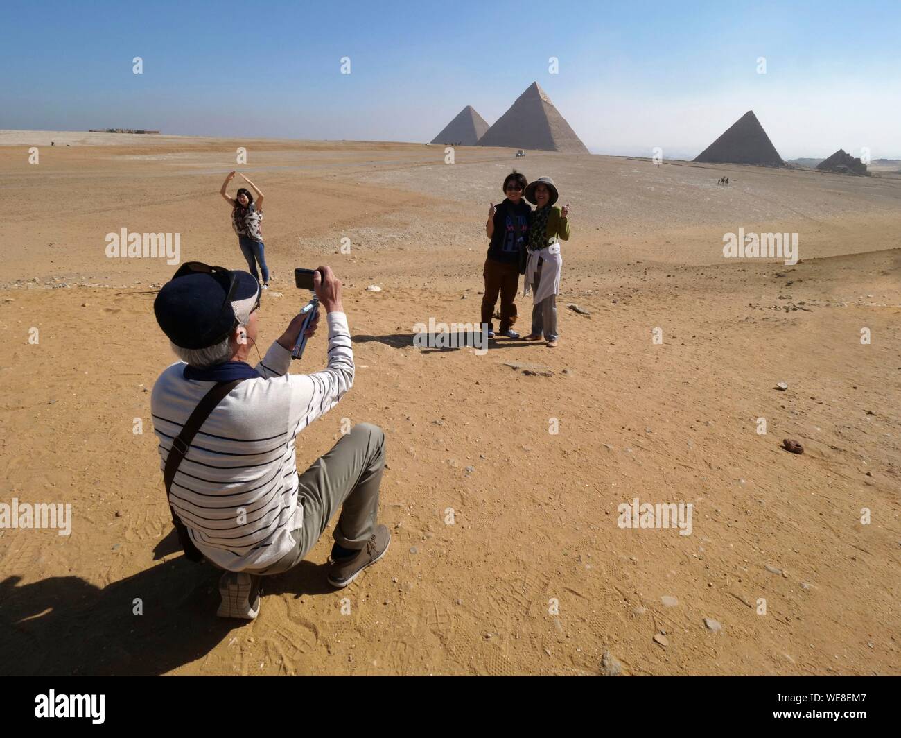 Egypt, Cairo, Giza, UNESCO Heritage Site, Pyramids of Giza, Group of tourists photographing in front of the pyramids of Kheops, Khephren and Mykerinos Stock Photo