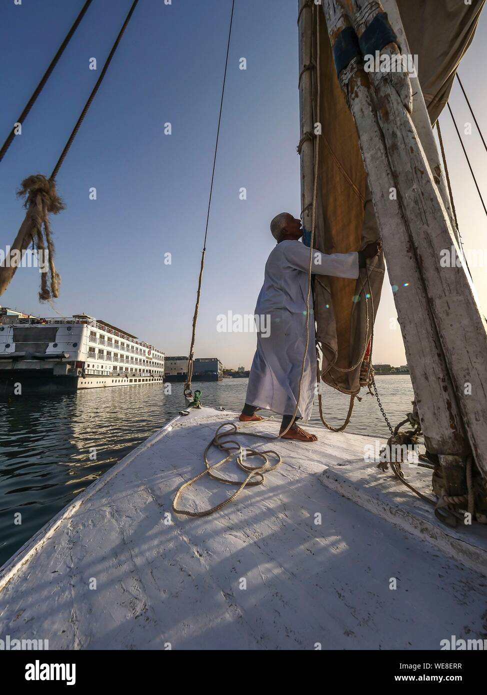 Egypt, Upper Egypt, Nubia, Nile Valley, Aswan, On board a felucca, the captain folds his sail before docking Stock Photo