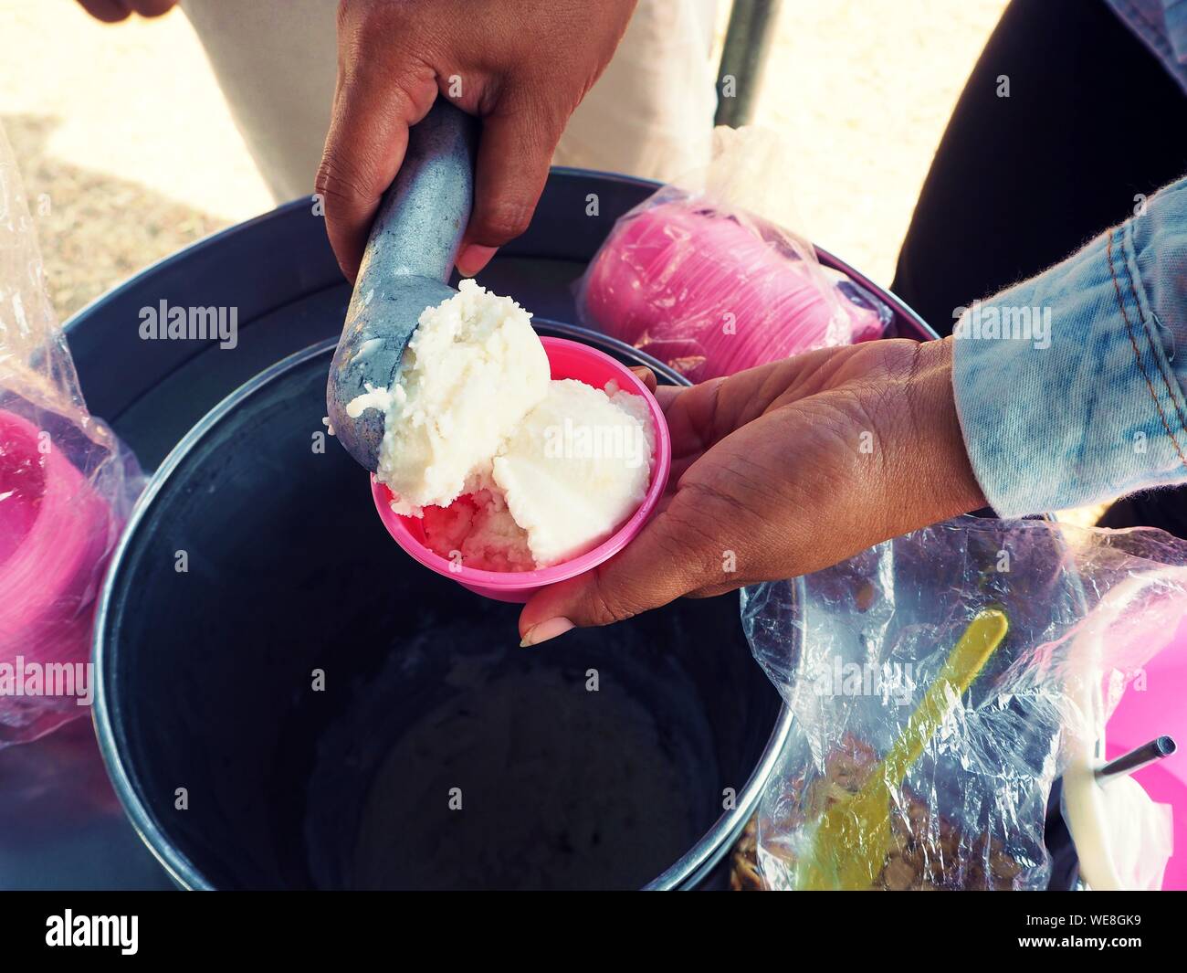 Hand holding a spoon to scoop the ice cream into the pink color cup Stock Photo