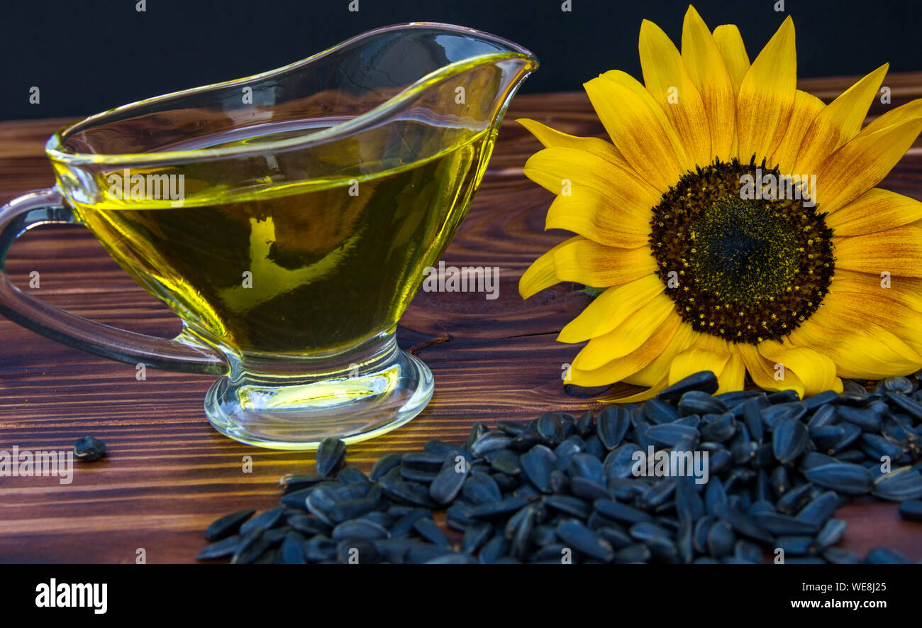 wooden background with sunflower oil, seeds and a sunflower Stock Photo