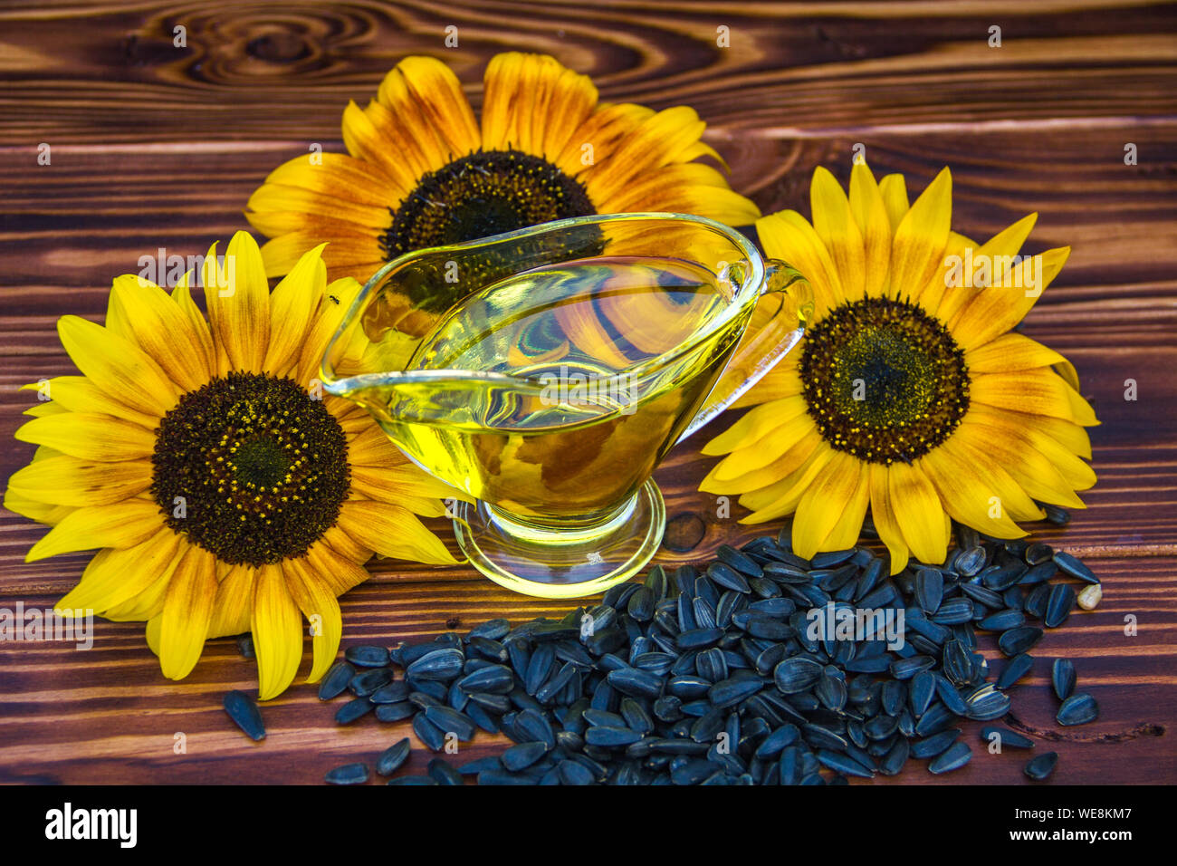 wooden background with sunflower oil, seeds and a sunflower Stock Photo