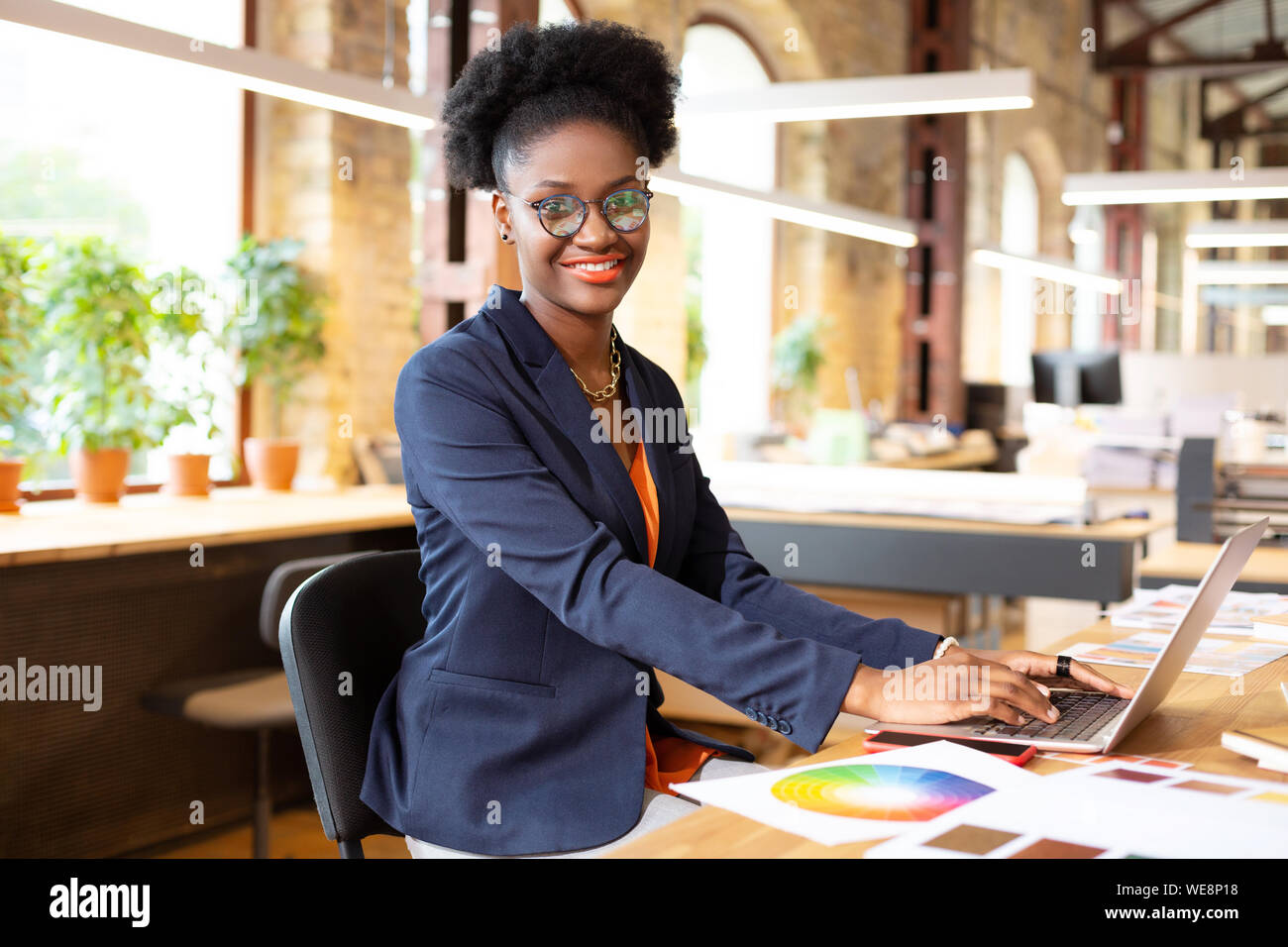 Interior designer smiling while typing e-mail for client Stock Photo