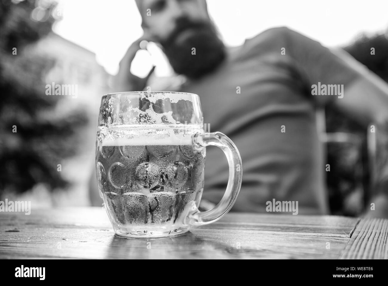 Drinking from a mug to keep things firmly in hand. Beer mug. Serving chilled beer in glass mug in pub. Large mug of refreshing drink on outdoor cafe table. To have and to hold and keep your beer cold. Stock Photo