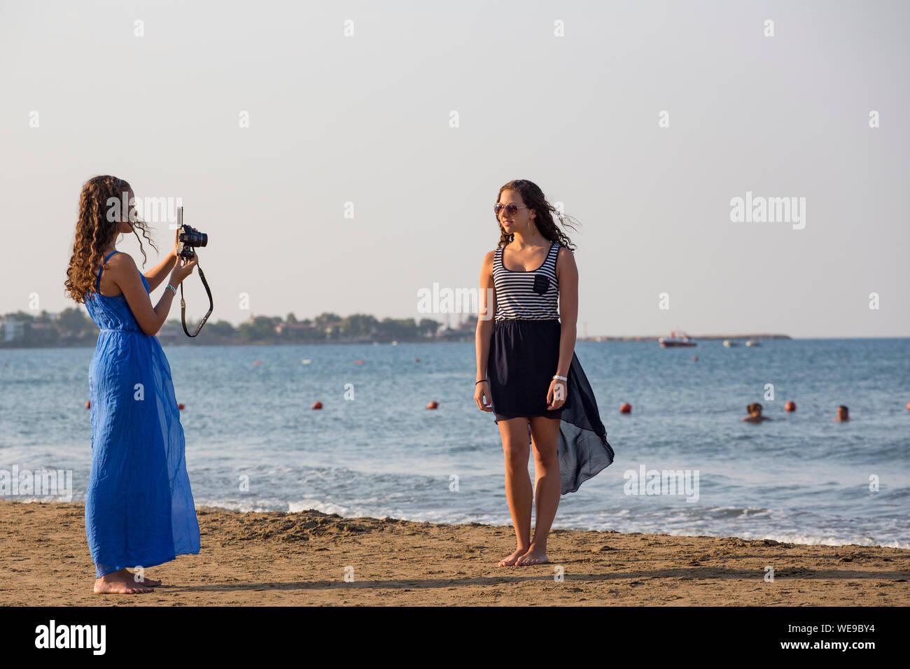 A young women takes a holiday photograph of another girl on a beach Stock Photo