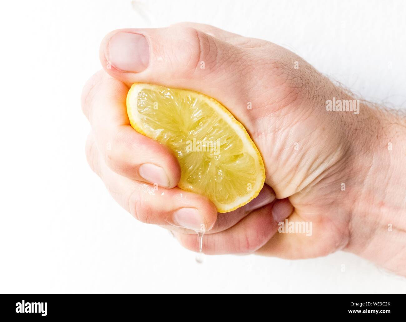 Cropped Hand Of Man Squeezing Lemon Stock Photo