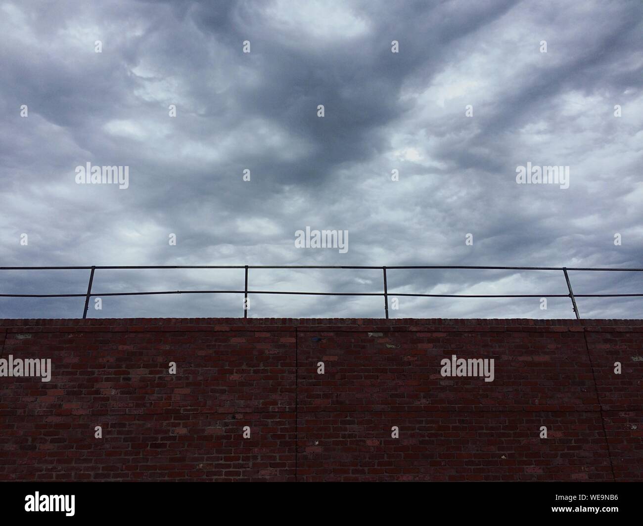 Low Angle View Of Stone Brick Wall Against Cloudy Sky Stock Photo