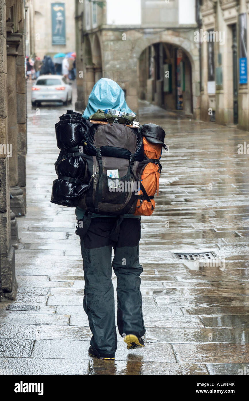 Pilgrim walking on rainy day street of old town of Santiago de Compostela. Pilgrimage or tourism on rainy day concept Stock Photo