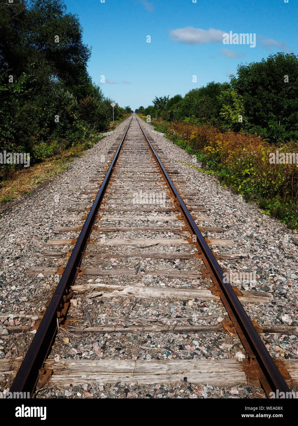 Railway tracks in a rural scene with a bright blue sky and white clouds Stock Photo