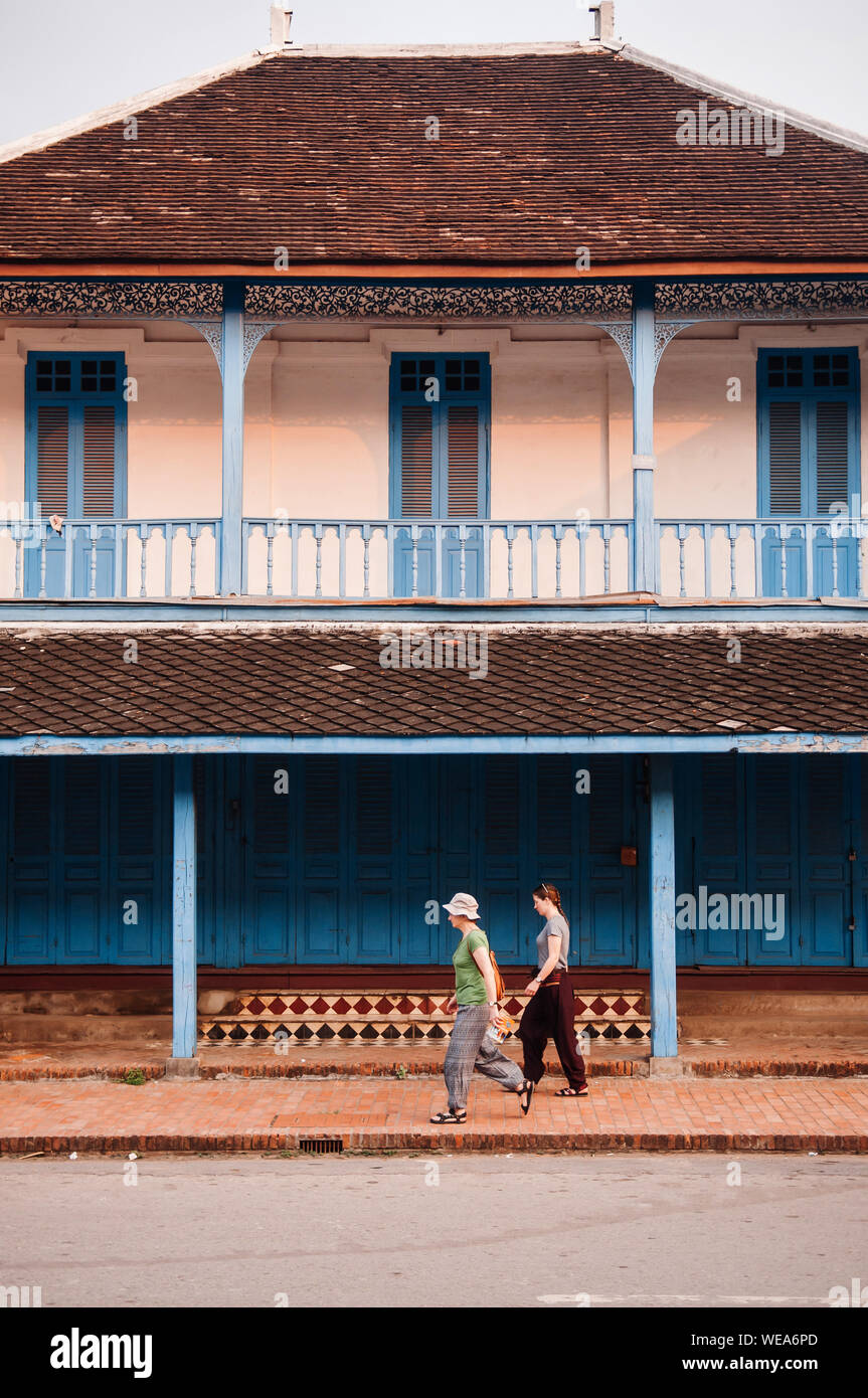 APR 4, 2019 Luang Prabang, Laos - Blue doors French Colonial building and European tourist on main street - Famous tourist district and morning walk Stock Photo