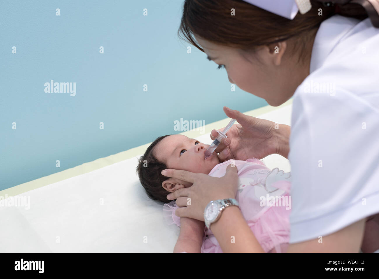 Side View Of Nurse Giving Vaccination Through Syringe To Baby Girl Stock Photo