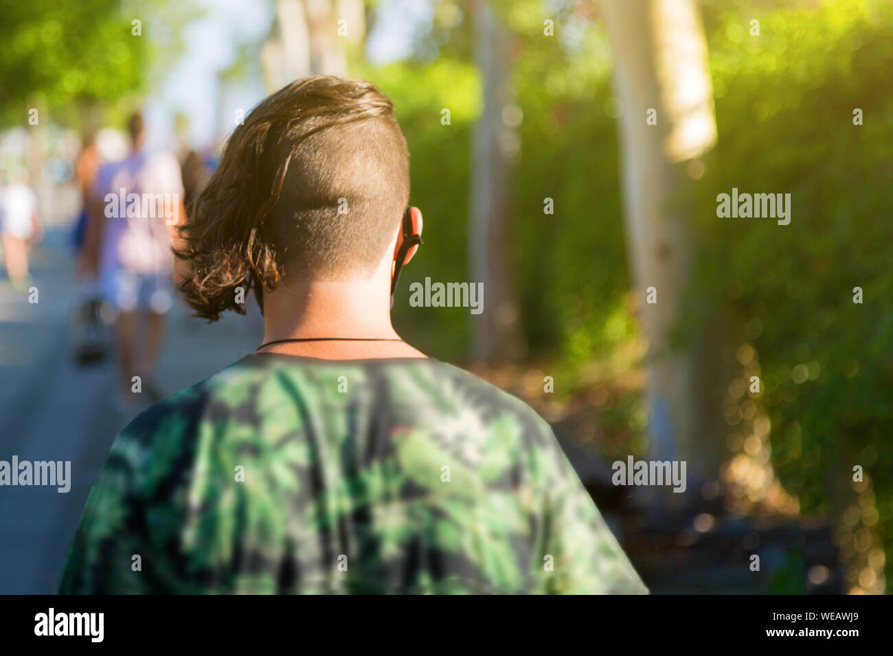 View from a pin on a man with a short haircut on his head as he walks along the street. Stock Photo