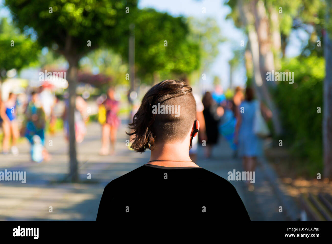 View from pin on a man with a short haircut on his head as he walks along the street Stock Photo