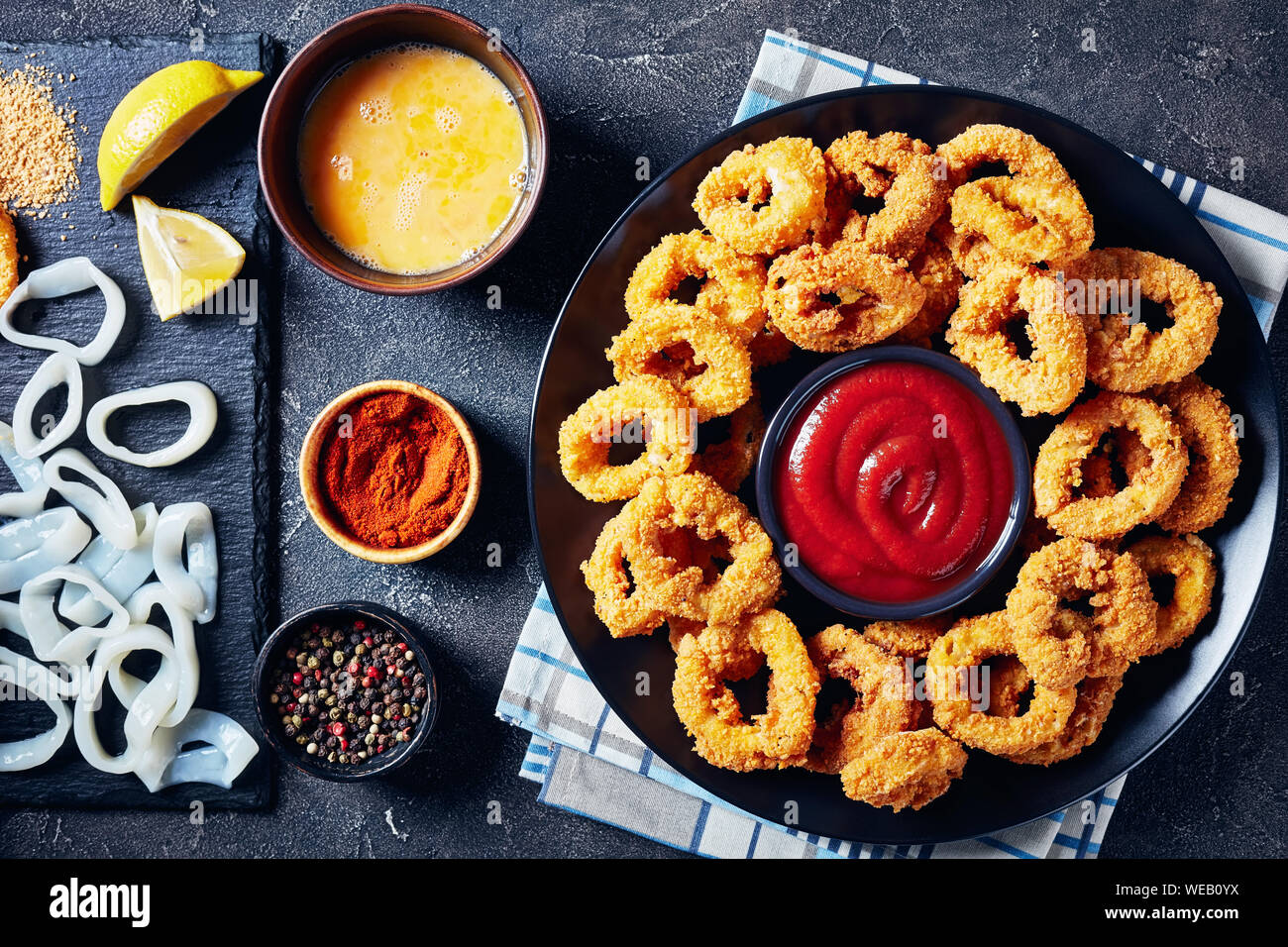 crispy calamari rings, deep fried breaded squid rings served with tomato  sauce on a black plate on a concrete table with ingredients, horizontal  view Stock Photo - Alamy