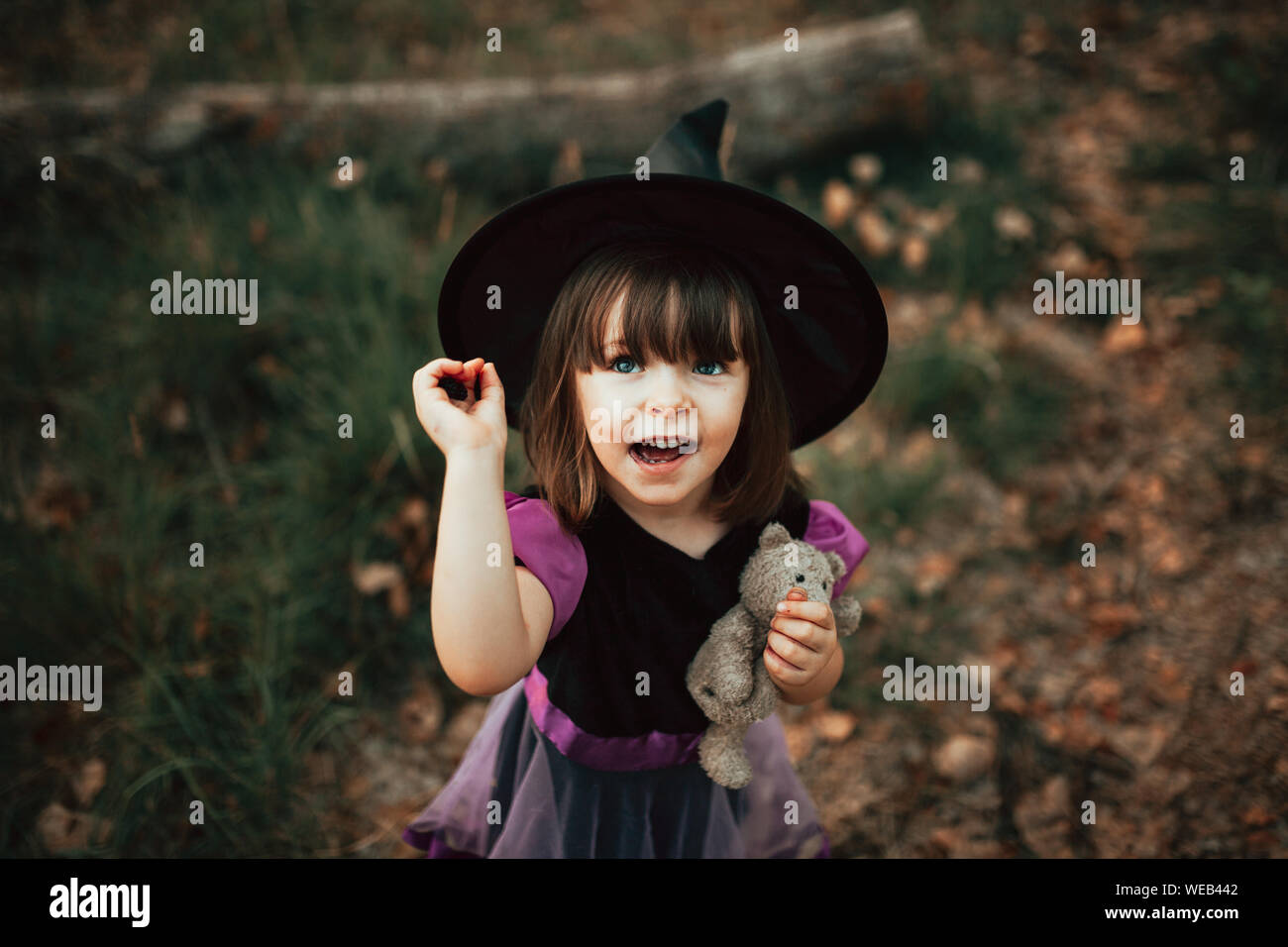 Smiling girl disguised as a witch in the woods during Halloween Stock ...