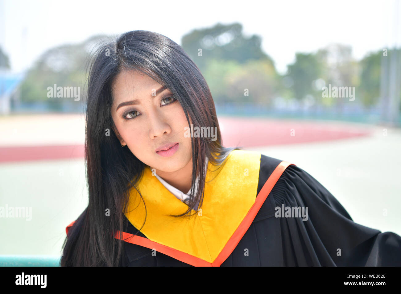 Portrait Of Beautiful Young Woman In Graduation Gown Stock Photo